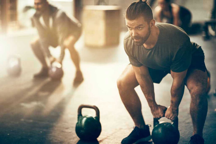 1043370892 Man lifting kettlebell in a gym setting