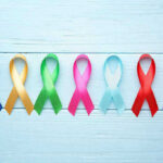 Colorful awareness ribbons on light wooden background
