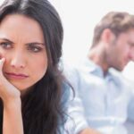 A woman looking concerned while a man appears distressed in the background