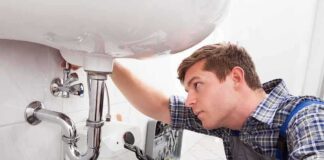 A plumber working under a sink with tools