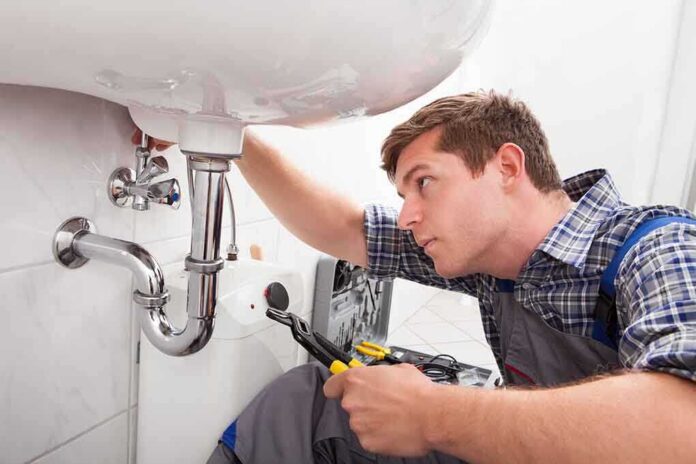 shutterstock_146630252.jpg A plumber working under a sink with tools