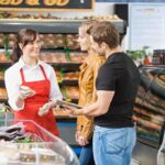 A grocery store employee assisting a couple with their shopping