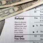 Close up of tax refund form with cash on a wooden surface