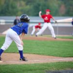 Young baseball player in blue uniform preparing to run on the field