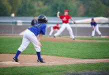 Young baseball player in blue uniform preparing to run on the field