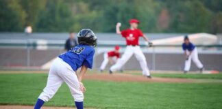 Young baseball player in blue uniform preparing to run on the field