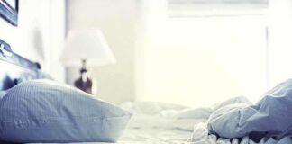 A cozy unmade bed with soft pillows and bedding in a well lit room