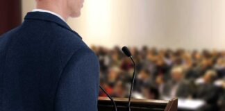 A speaker at a podium addressing an audience