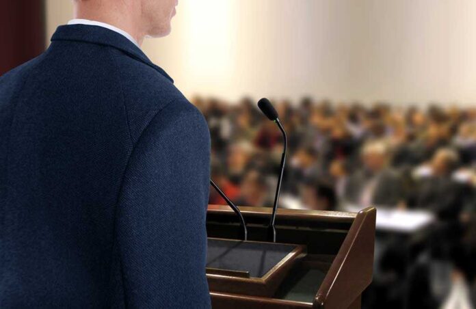 shutterstock_200679422.jpg A speaker at a podium addressing an audience