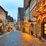 A picturesque street adorned with holiday lights and decorations in the evening