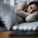 A woman lying on a couch looking contemplative and distressed