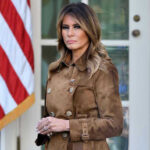 Woman in brown coat beside American flag