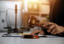 Hand holding gavel with scales in background