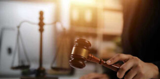 Hand holding gavel with scales in background