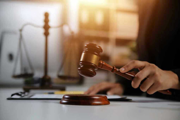 2478909667 Hand holding gavel with scales in background
