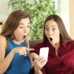 Two women look surprised at a phone