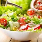 Fresh salad being drizzled with olive oil
