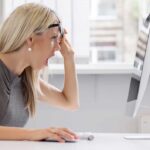 A woman with blonde hair showing a surprised expression while looking at a computer