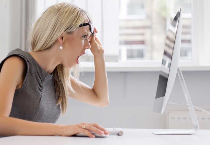 shutterstock_210593740.jpg A woman with blonde hair showing a surprised expression while looking at a computer