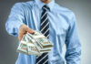 Person handing over a stack of money.
