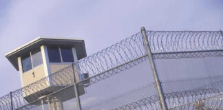 Guard tower behind barbed wire fence in a prison.