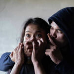 Trafficking Nightmare EXPOSED in San Diego Man holding womans mouth, gesturing silence.