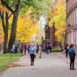 People walking on a college campus in autumn.
