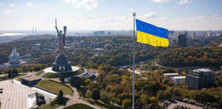 Large Ukraine flag with cityscape in background.