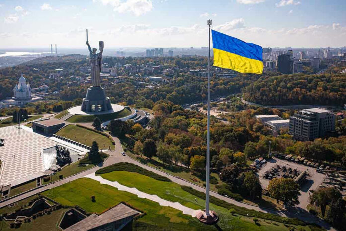 Large Ukraine flag with cityscape in background.
