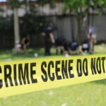 Yellow crime scene tape blocking grassy area.