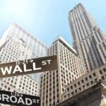 Tiny Firm’s 55,000% Stock Jump Stuns Wall Street Street signs for Wall Street and Broad Street with skyscrapers in the background