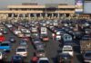A crowded parking lot filled with cars near a border crossing