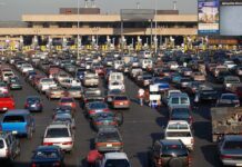 A crowded parking lot filled with cars near a border crossing