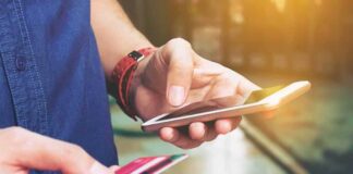 Person holding a smartphone and a credit card, preparing for a digital transaction