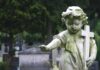 Weathered statue of a child angel holding a cross in a cemetery