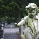 Weathered statue of a child angel holding a cross in a cemetery