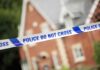 Domestic Violence Ignored Until Fatal Shooting Police tape reading POLICE DO NOT CROSS in front of a house