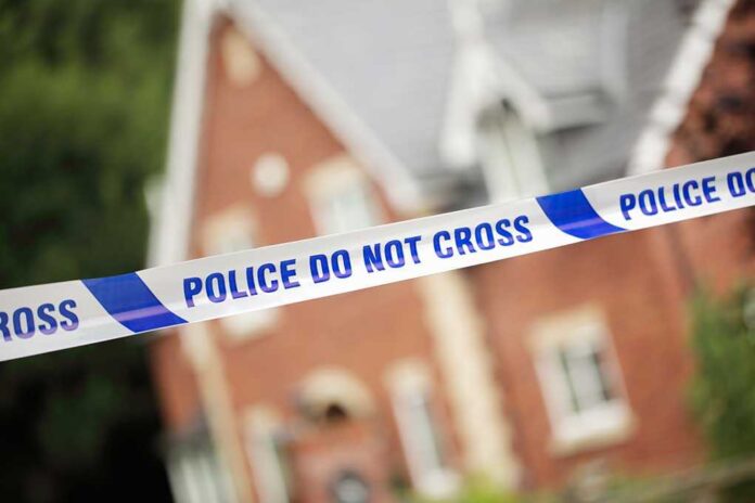 shutterstock_208616551.jpg Police tape reading POLICE DO NOT CROSS in front of a house