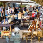 A bustling flea market with various antique items and furniture for sale
