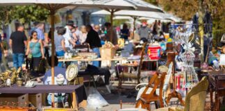 A bustling flea market with various antique items and furniture for sale
