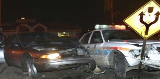 A damaged car and a police vehicle involved in a nighttime accident