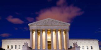 The Supreme Court building illuminated at night with a clear sky