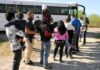 Families and children waiting in line near a bus