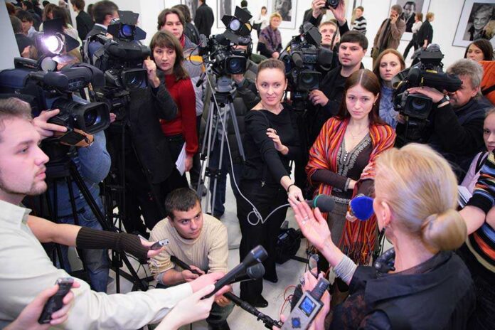 A crowded press conference with journalists and cameras surrounding a speaker