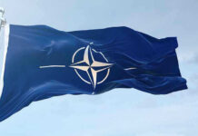 NATO flag waving against blue sky.