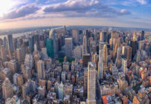 Aerial view of city with skyscrapers and cloudy sky.