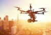 A drone flying over a city skyline during sunset