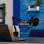 Laptop and a microphone on a desk.