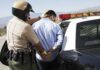 Police officer arresting a suspect near a patrol car