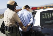 Police officer arresting a suspect near a patrol car